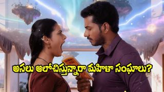 A dramatic still from Purushaha movie showing a man holding a book while a woman reacts emotionally, set against a surreal and visually striking background.